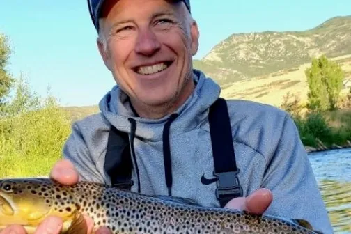 a smiling man holding a fish